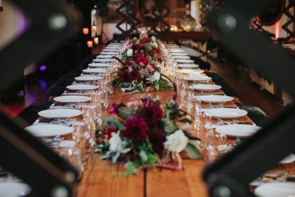Long wedding reception table set with place settings and flowers