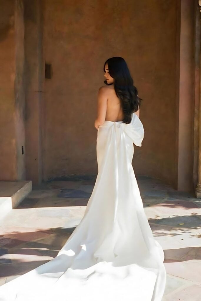 rowedding dress featuring a high slit, an open back and a detachable bow detail