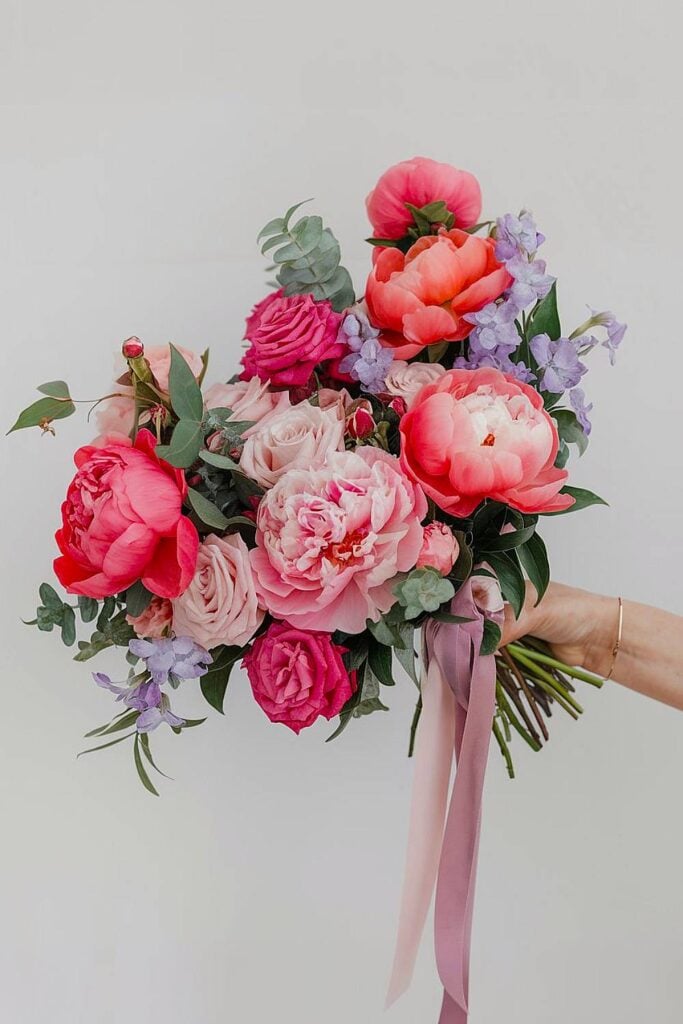 Peony bridal bouquet with coral blooms and pink roses.