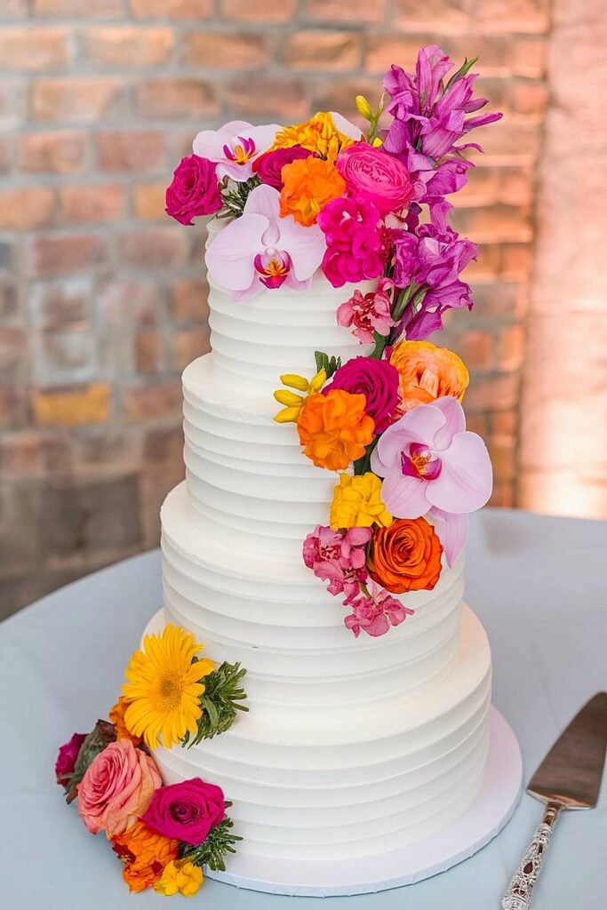 Bright flower wedding cake with vibrant floral cascade.