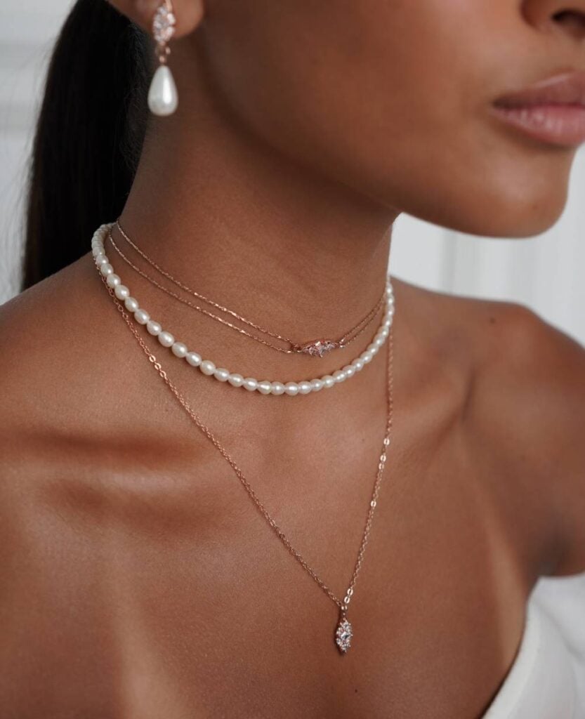 Delicate beach wedding accessories with layered pearl necklaces.