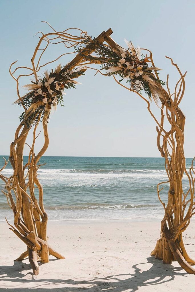 Driftwood beach wedding arch with floral accents.