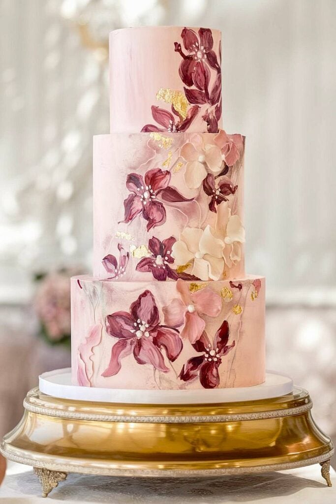 Hand-painted floral wedding cake with gold accents.