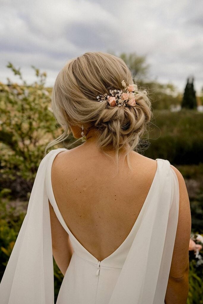 Bride’s loose updo with pink flowers for backyard wedding.