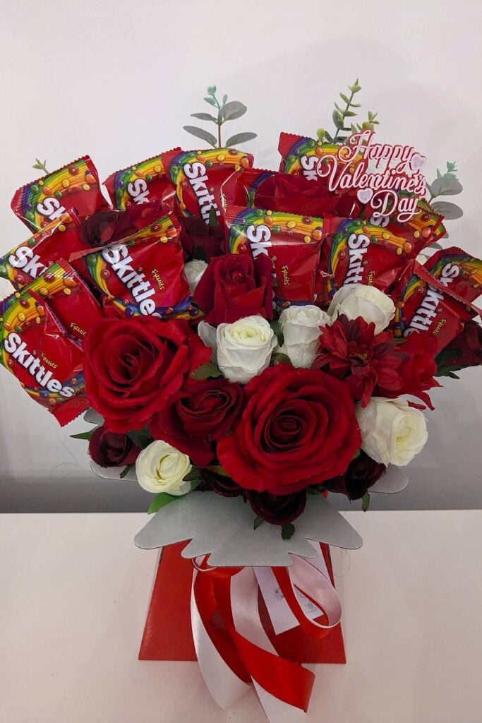 Skittles candy bouquet with red and white roses.