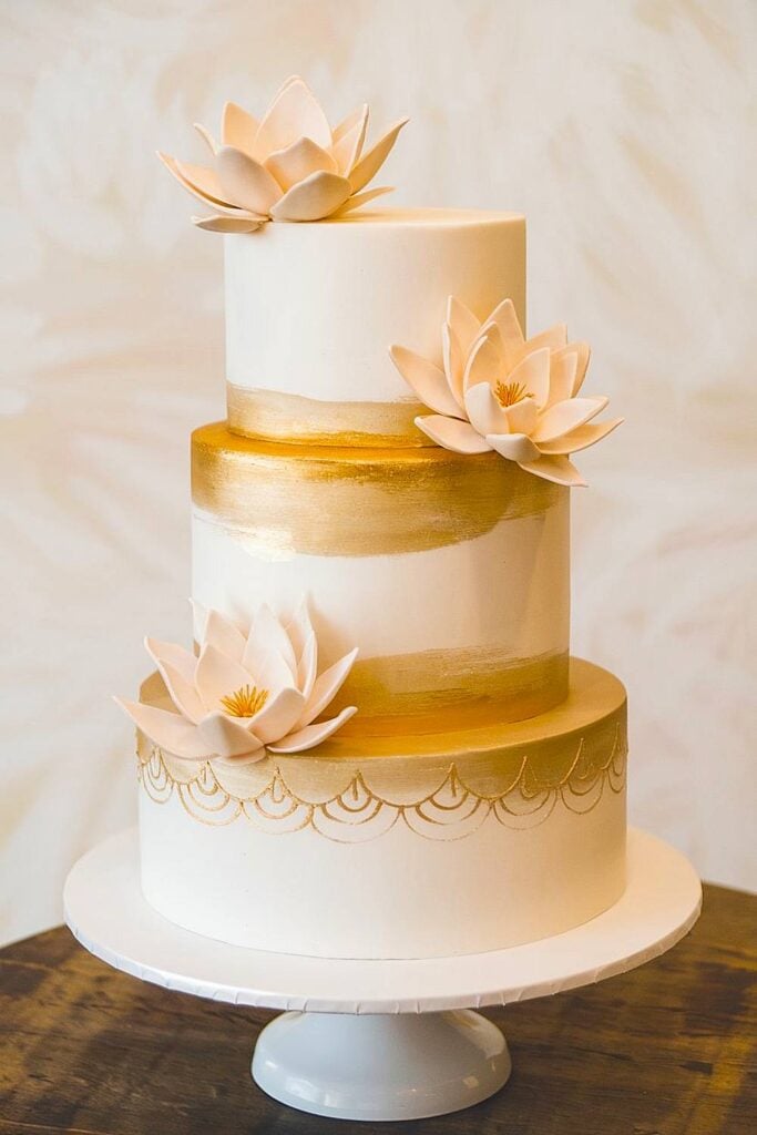 Wedding cake with lotus flowers and gold accents.