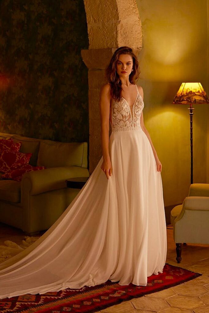 Deep v boho wedding dress with lace bodice and flowing train.