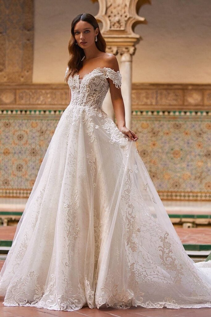 Off shoulder fairytale wedding dress with lace bodice and flowing skirt.