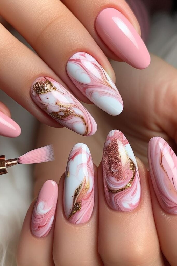 Pink-and-white marble swirl nails with gold foil accents