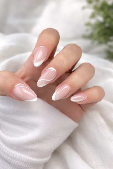 Sheer nude nails with white swooping French lines and negative-space curves