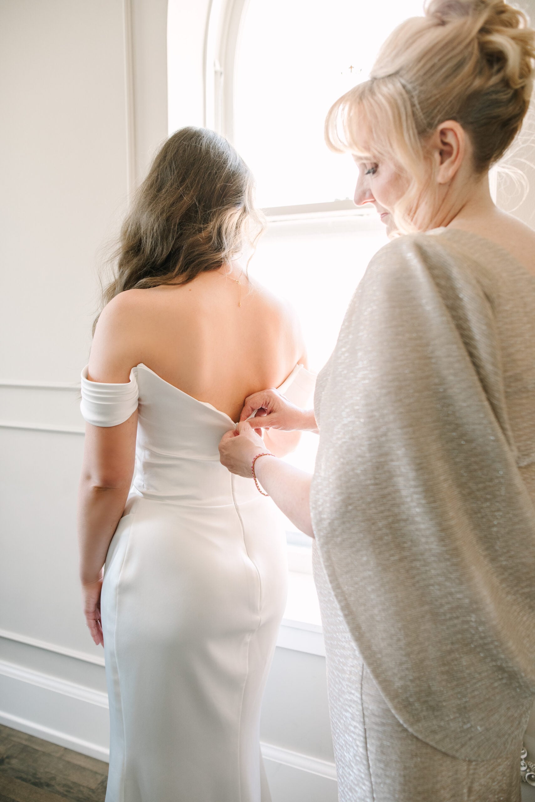 Abigail's mom in a champagne gown buttoning the back of her wedding dress