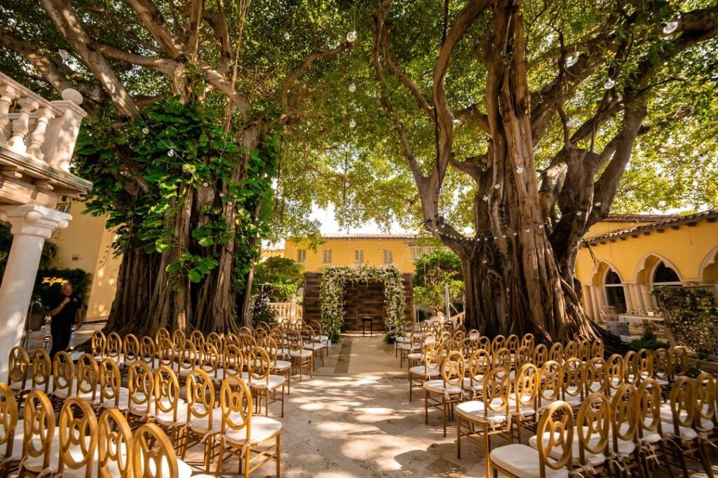 Villa Woodbine outdoor wedding ceremony under canopied banyan trees in Coconut Grove, Miami — Mediterranean estate venue