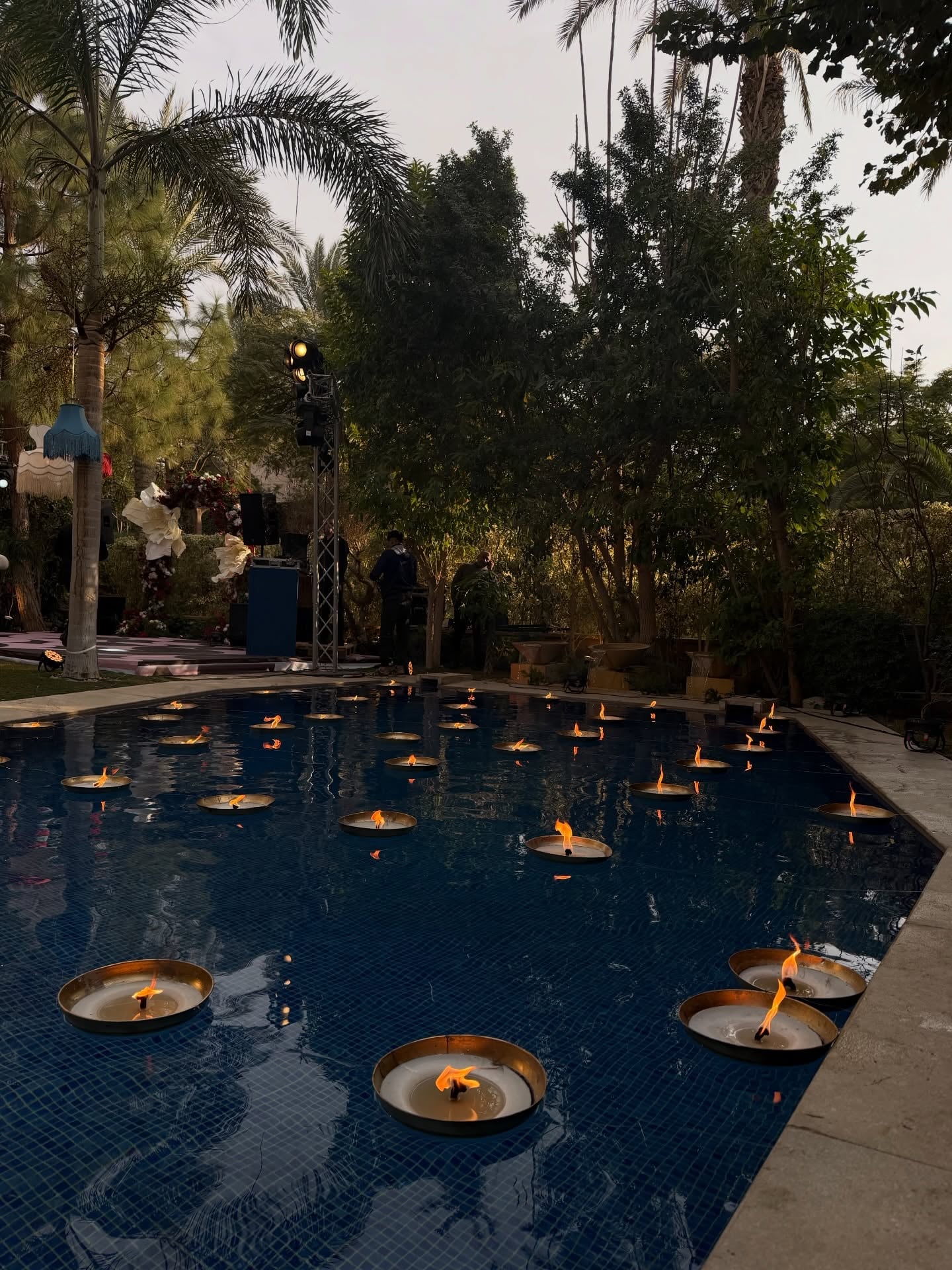 Large bowl floating candles in pool with palm trees at outdoor wedding reception