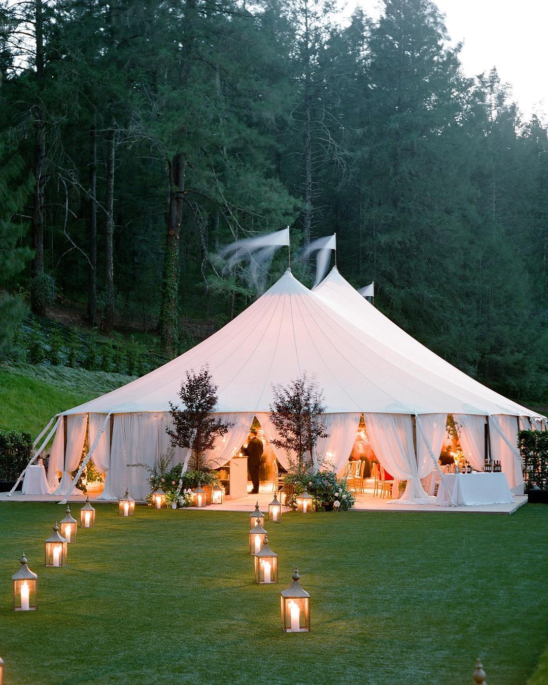 Sailcloth tent glowing at twilight with lanterns lining grass path, Meadowood Napa wedding by Jose Villa