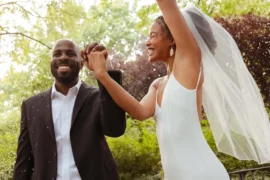 Couple celebrating at their wedding ceremony in a sunny green park, bride in veil and groom in suit