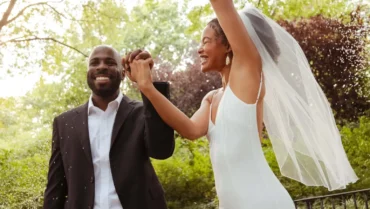 Couple celebrating at their wedding ceremony in a sunny green park, bride in veil and groom in suit