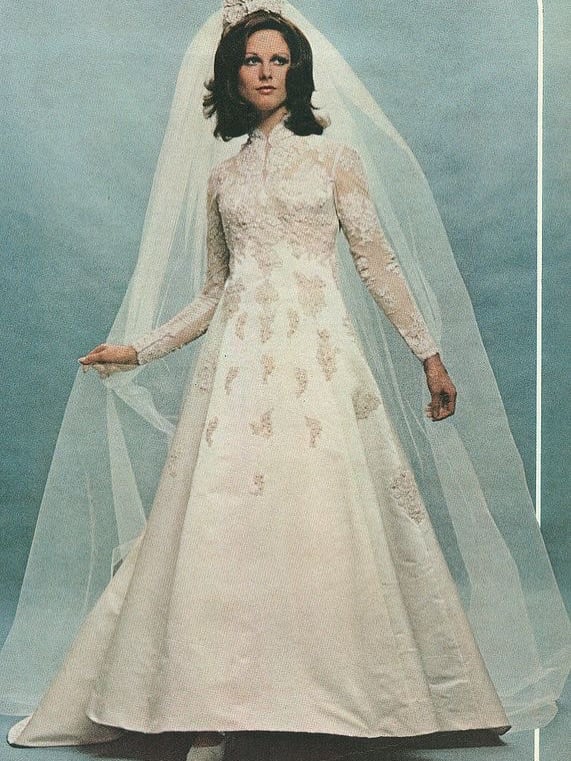 1970s bride in a high-neck lace gown with appliques and a short pouf veil