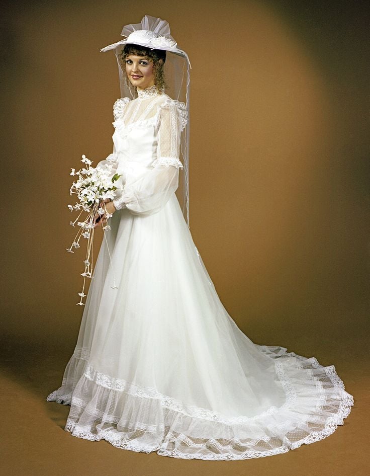 1970s bride in a gown with bishop sleeves and a wide-brimmed picture hat with a veil