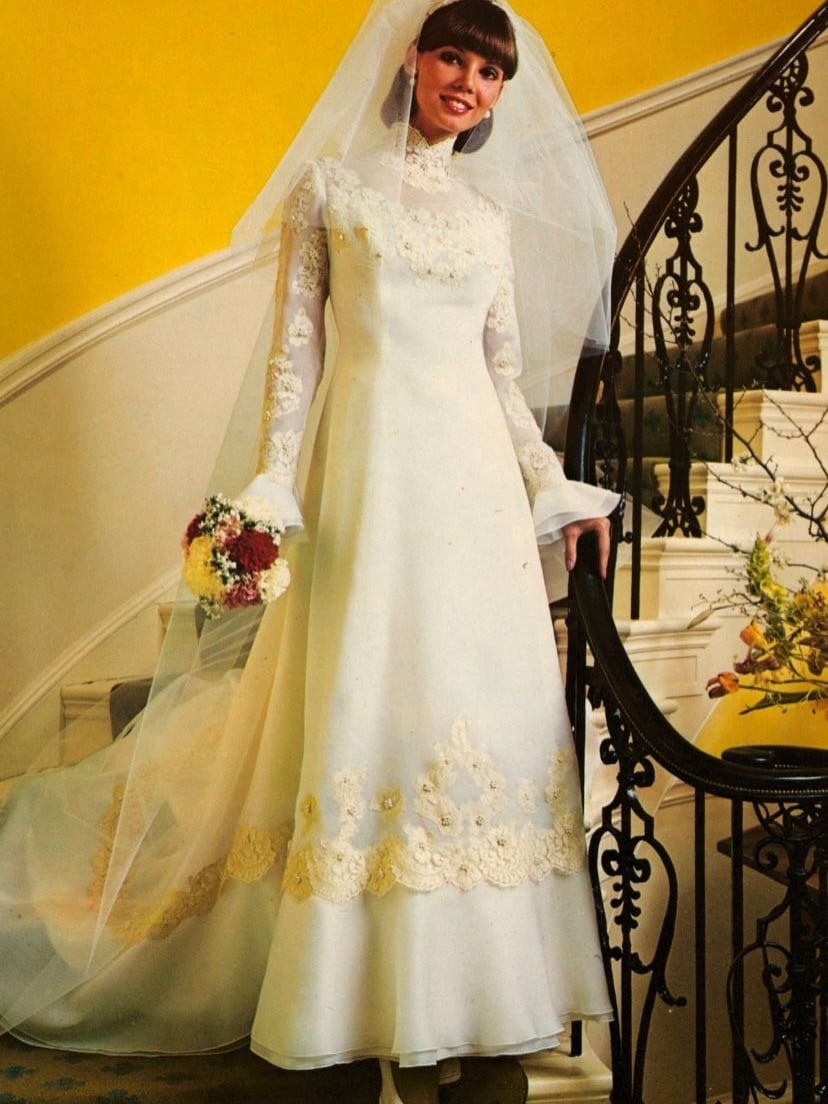 1970s bride with blunt bangs on a curved staircase in front of a yellow wall