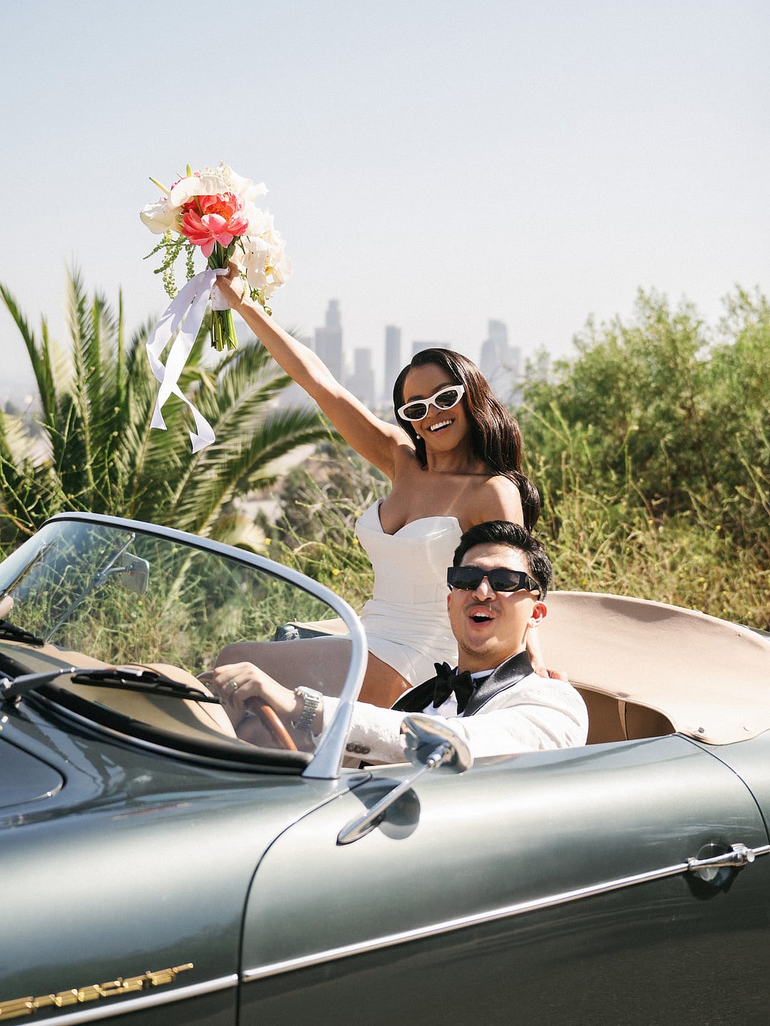 The couple celebrating in the car with the bouquet raised