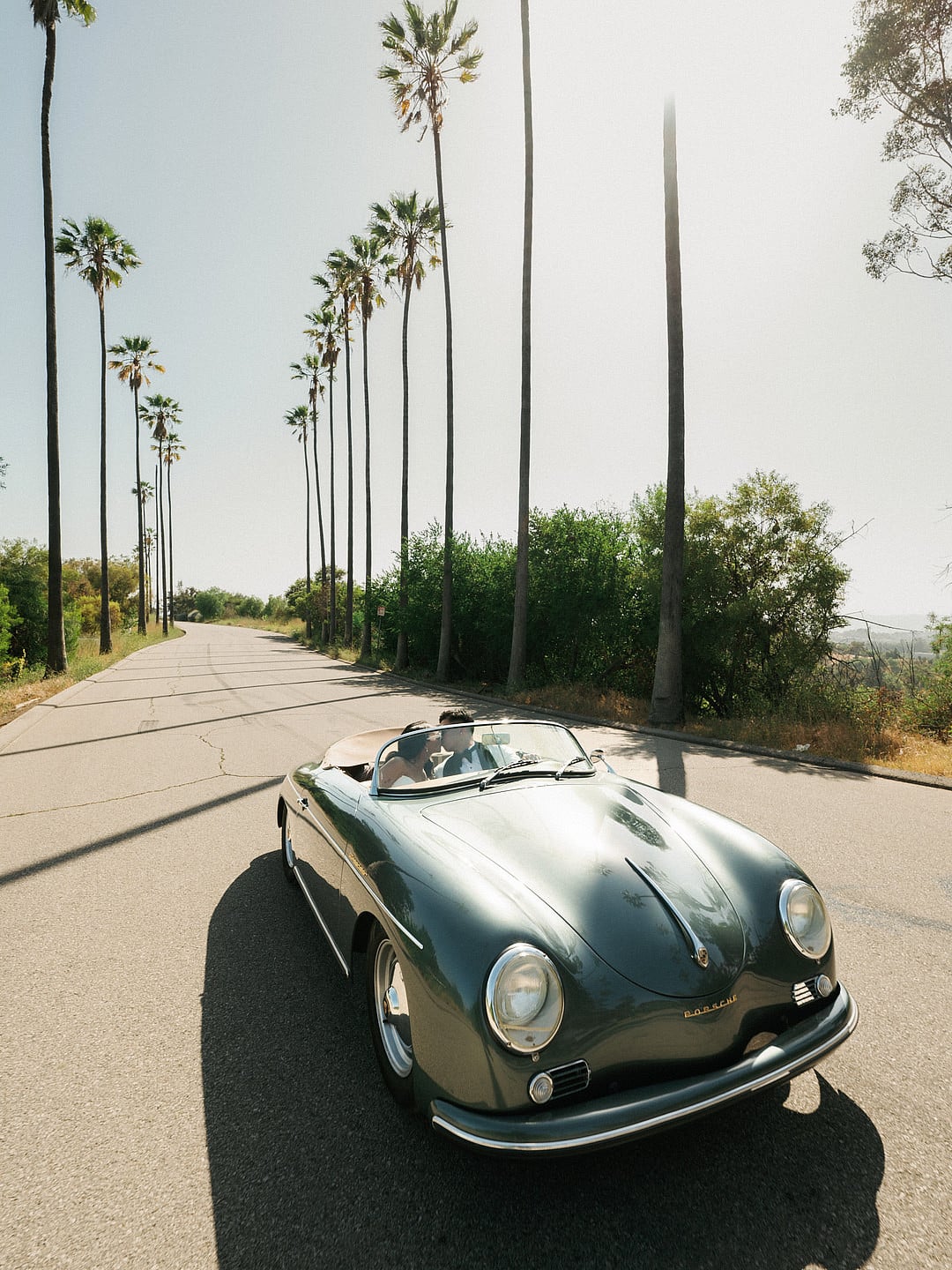 The vintage Porsche on a palm-lined road