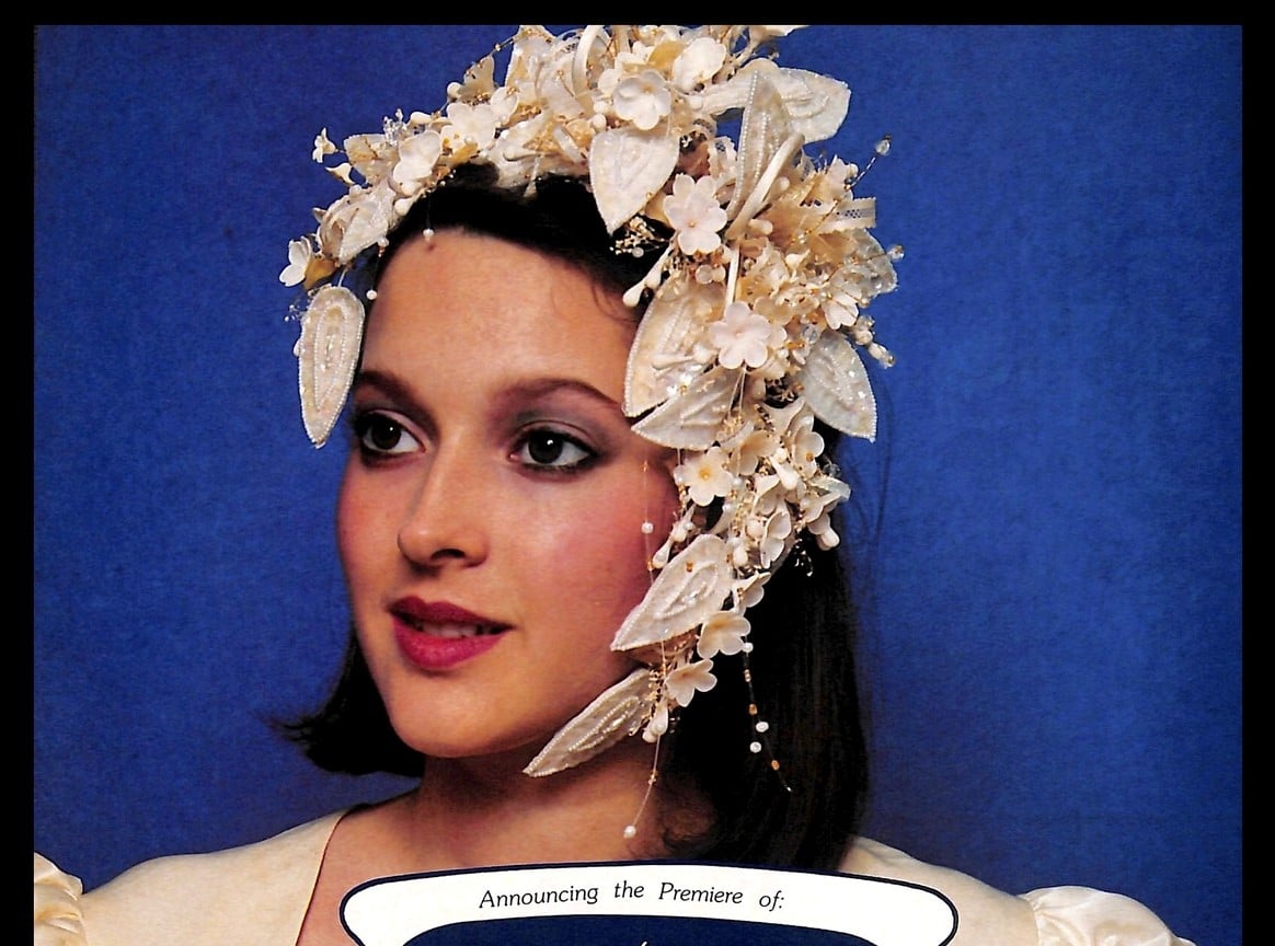 1988 Coronation Collection ad, bride in a large porcelain flower headpiece against a royal blue background