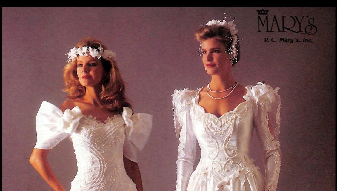 1988 P.C. Mary's ad, one bride with long full curls worn down under a flower halo, one with swept-up hair and baby's breath
