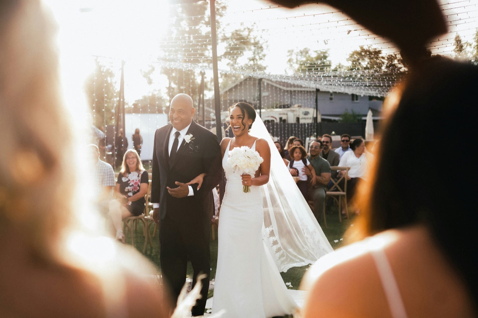 Bride laughing as her father walks her down the aisle at an outdoor wedding ceremony