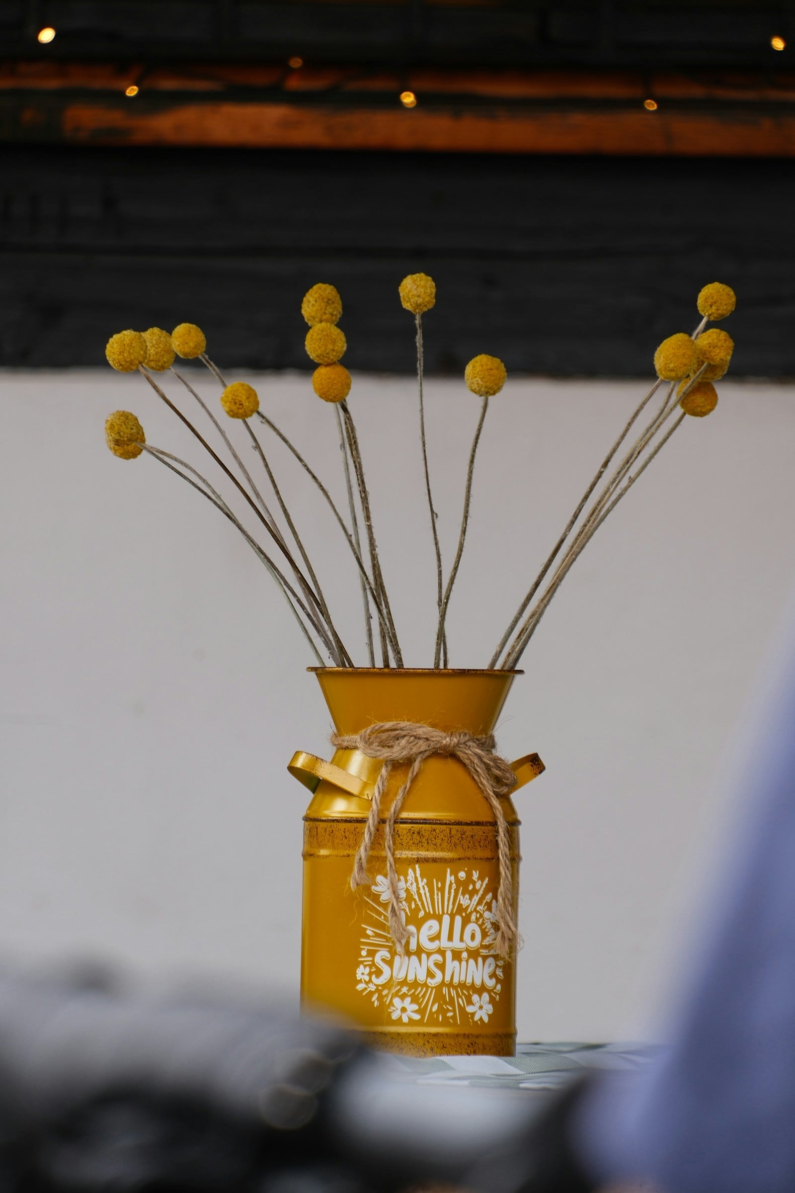 Yellow craspedia billy balls arranged in a rustic yellow milk can