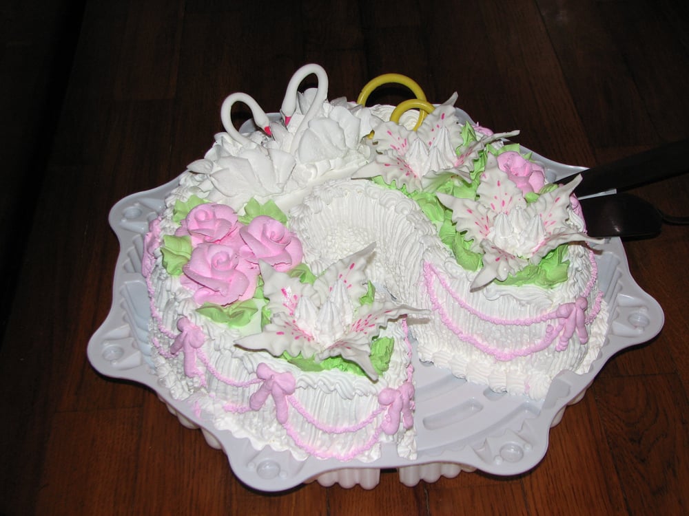Overhead view of the swan wedding cake showing it is two heart-shaped cakes joined together, decorated with pink piped roses, ruffled borders, and green leaves