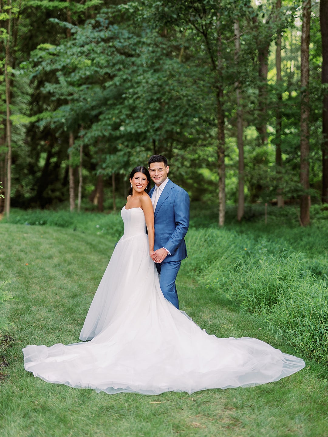 Quinn's full wedding gown and train against the green Ohio woods