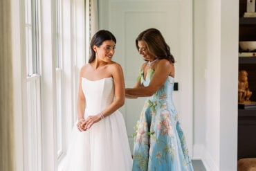 Quinn getting into her wedding dress with her mom in a floral gown
