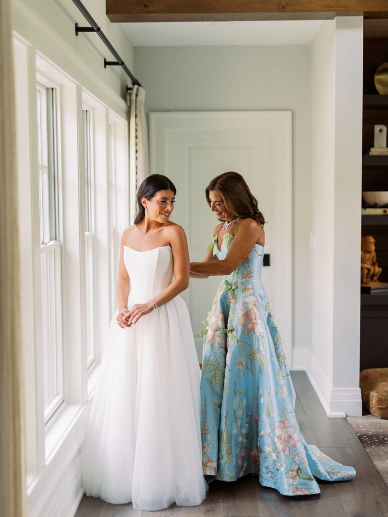 Quinn getting into her wedding dress with her mom in a floral gown