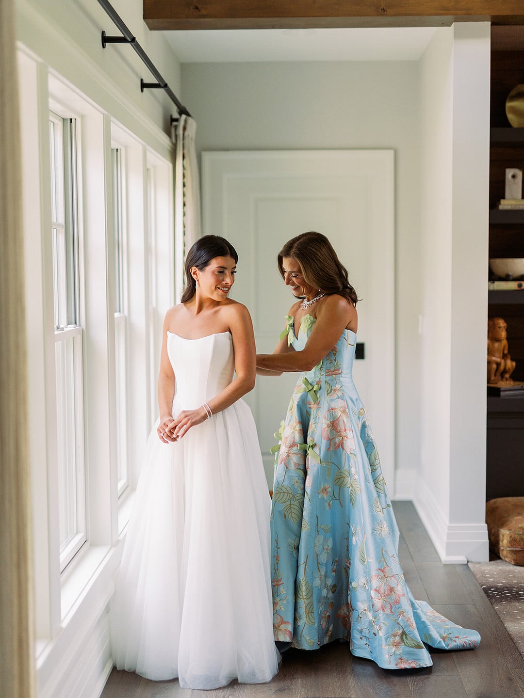 Quinn getting into her wedding dress with her mom in a floral gown