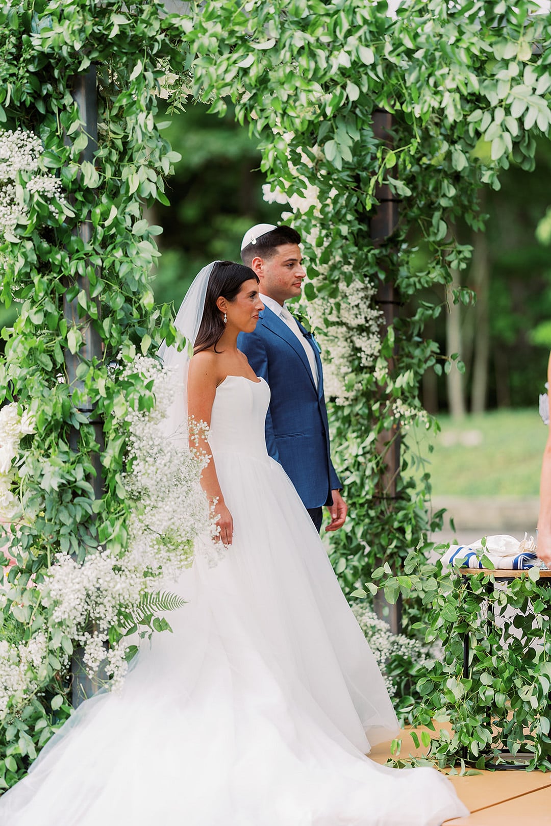 Quinn and Michael standing under the greenery chuppah during their ceremony
