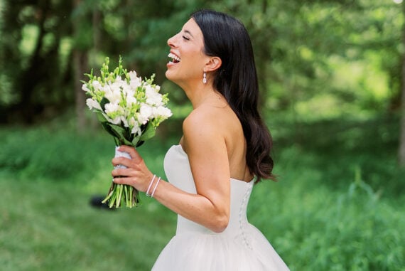 Quinn laughing and holding her white bouquet during summer garden wedding portraits in Ohio