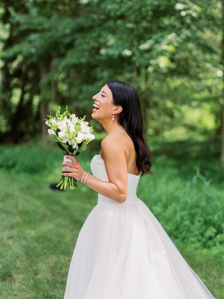 Quinn laughing and holding her white bouquet during summer garden wedding portraits in Ohio