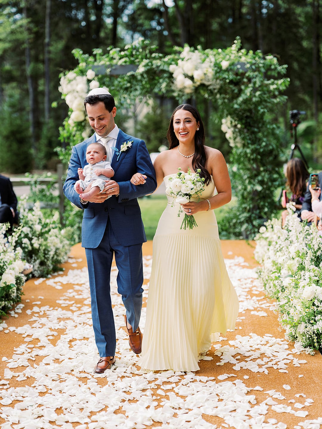 Quinn walking down the petal aisle with her parents