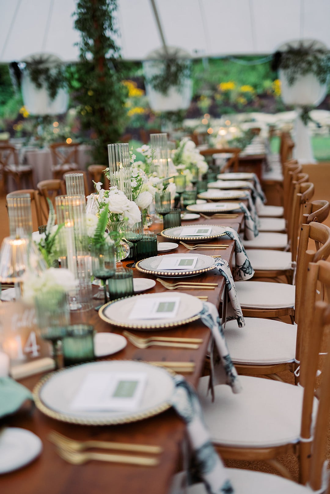 Long reception tables under the tent with greenery and candlelight