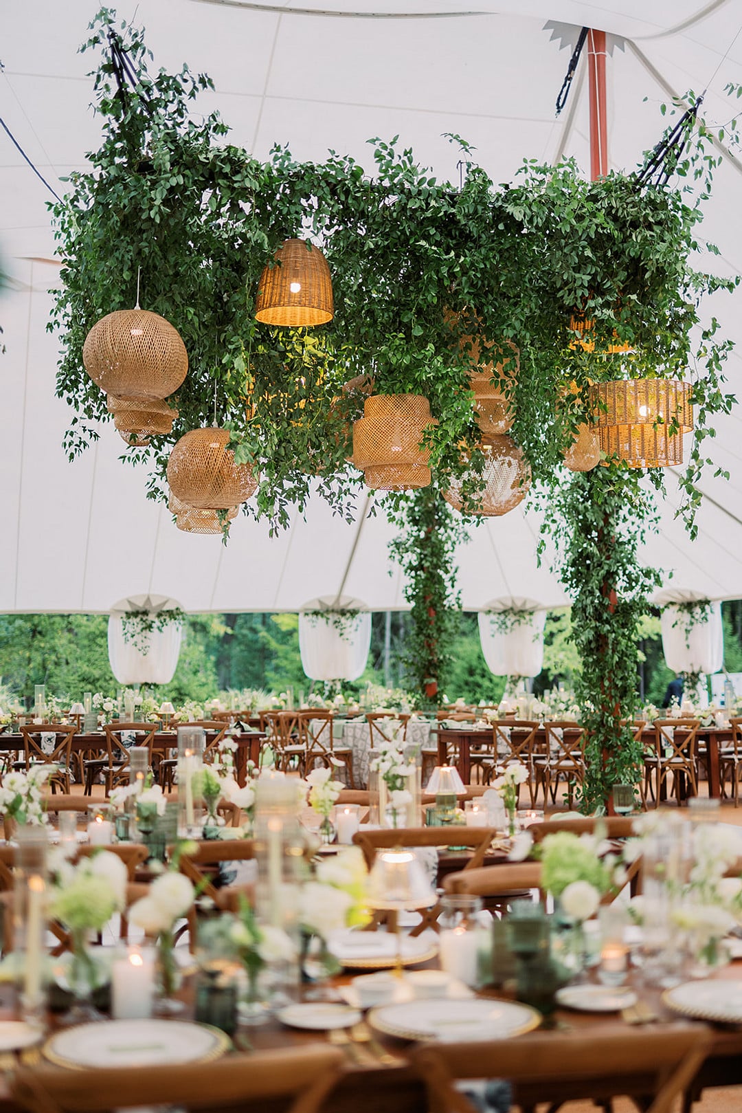 Reception tent with hanging greenery and woven rattan lanterns