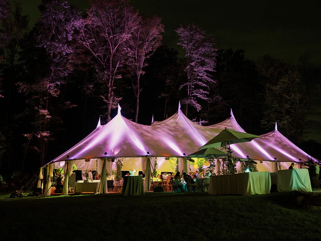 The sailcloth reception tent glowing at night in the Ohio woods