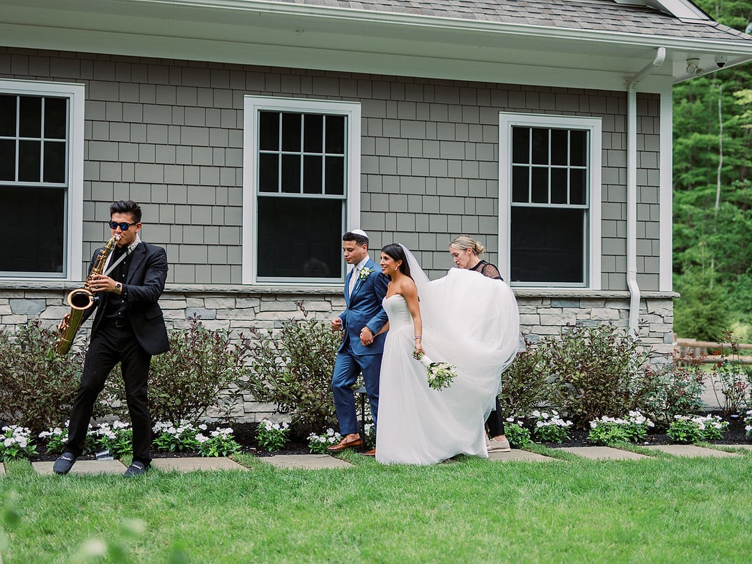 A roaming saxophone player leading Quinn and Michael across the lawn