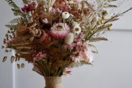 Rustic dried wedding bouquet with strawflowers, statice, bunny tail grass and ferns wrapped in burlap
