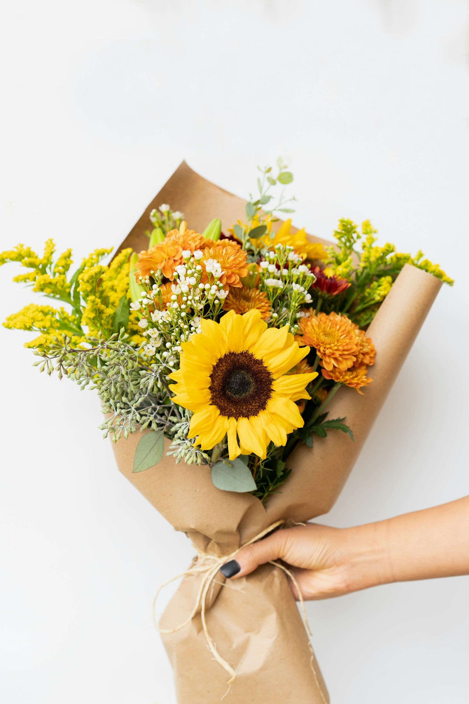 Sunflower bouquet wrapped in kraft paper with yellow solidago