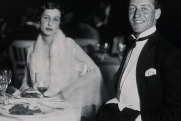Vintage couple in formal attire seated at a wedding reception dinner table