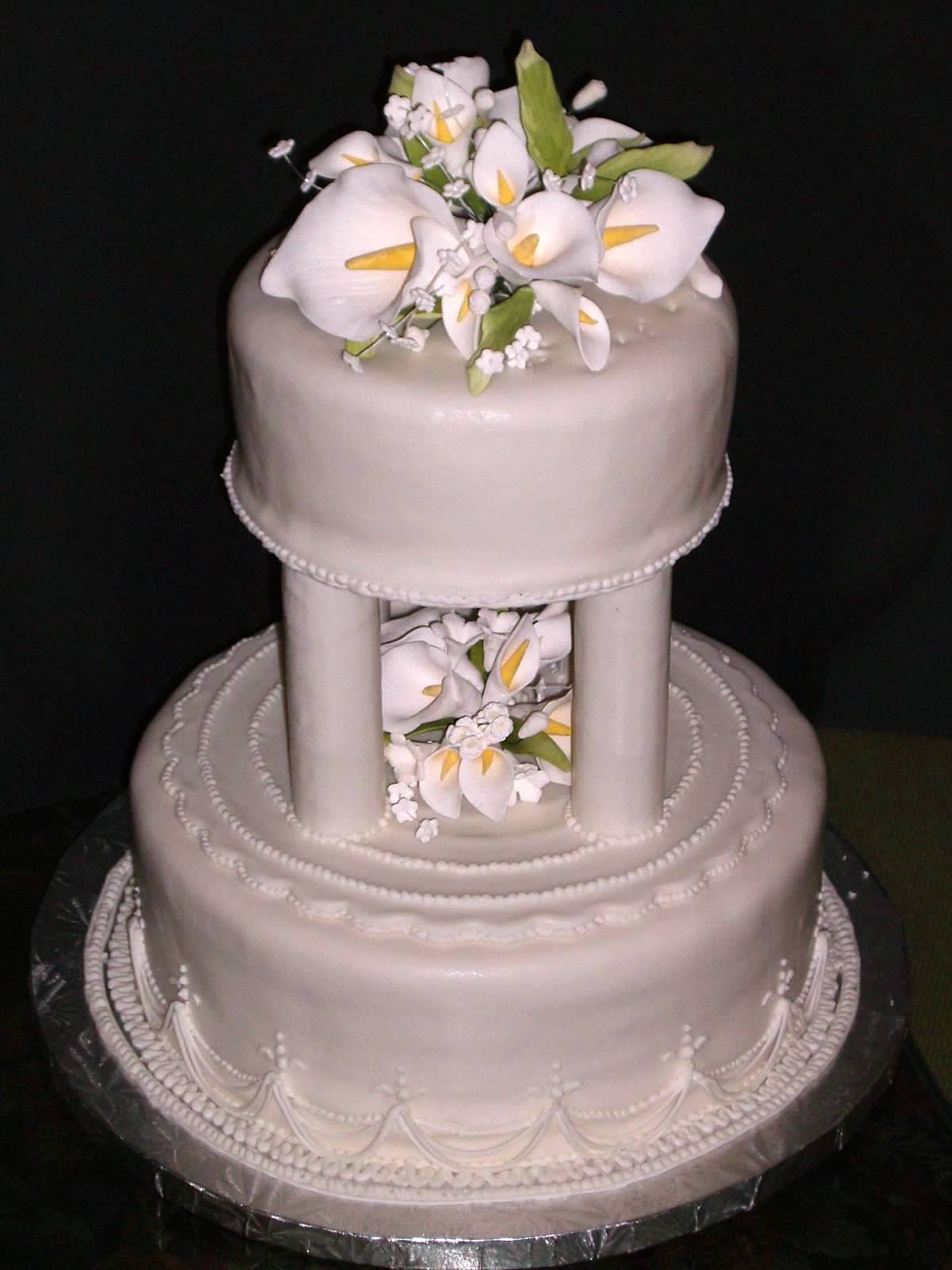 Tiered wedding cake with a colonnade middle tier holding fondant calla lilies between the columns