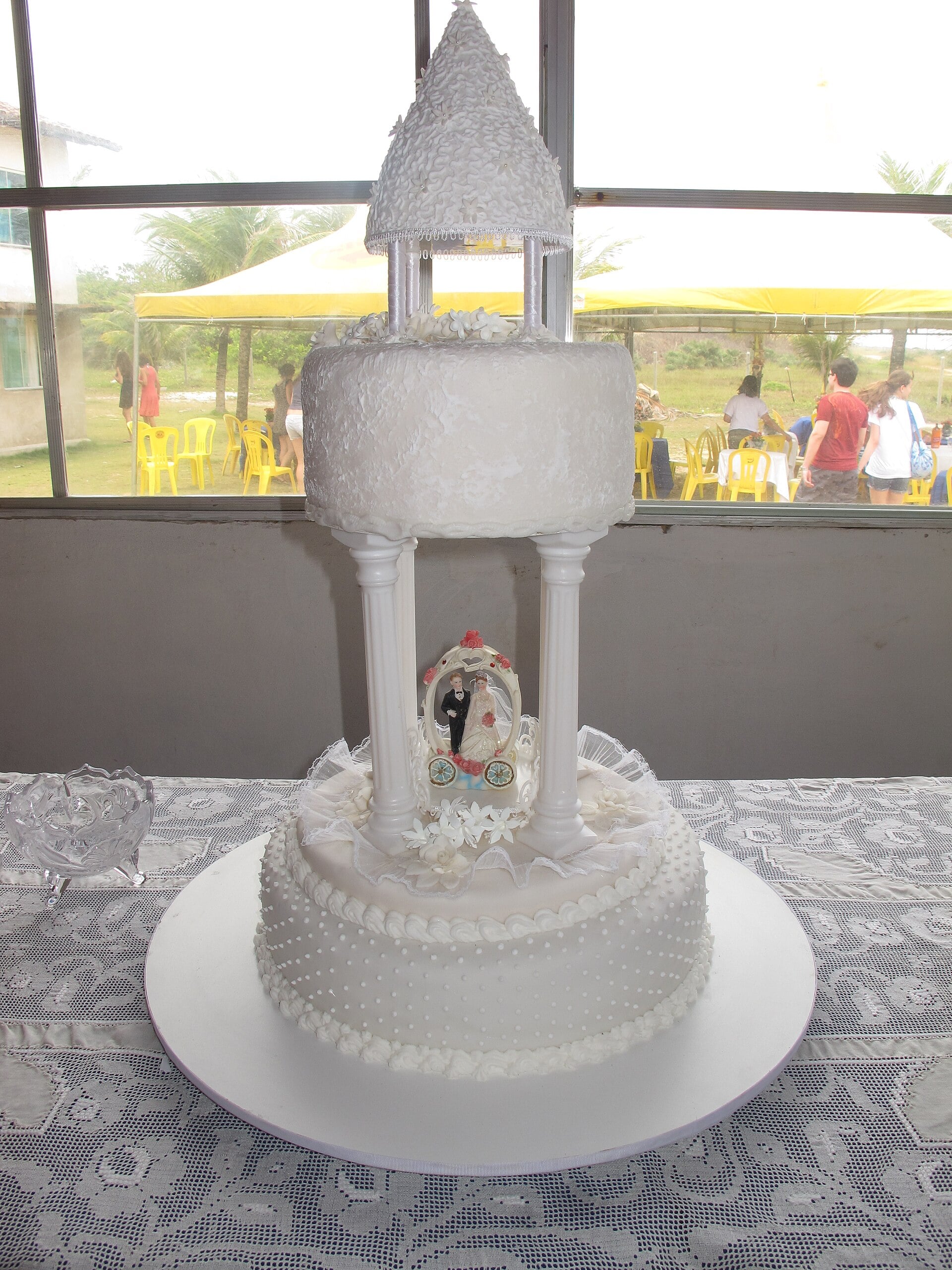 Wedding cake with a pillared gazebo top tier holding a small bride and groom topper under its roof