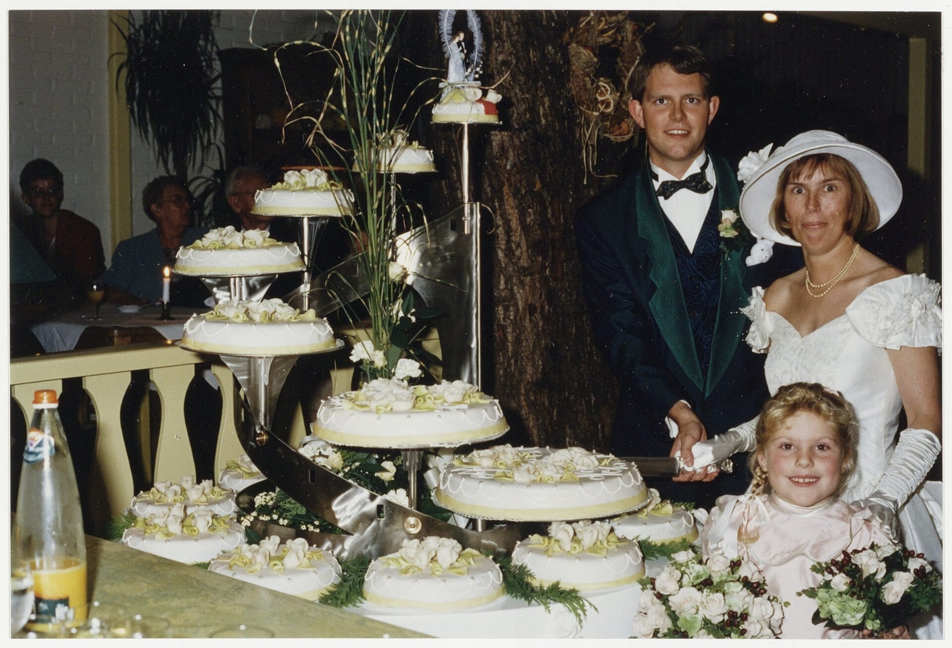 Bride and groom cutting a towering wedding cake made of many small satellite cakes arranged on a spiral chrome staircase stand, 1994