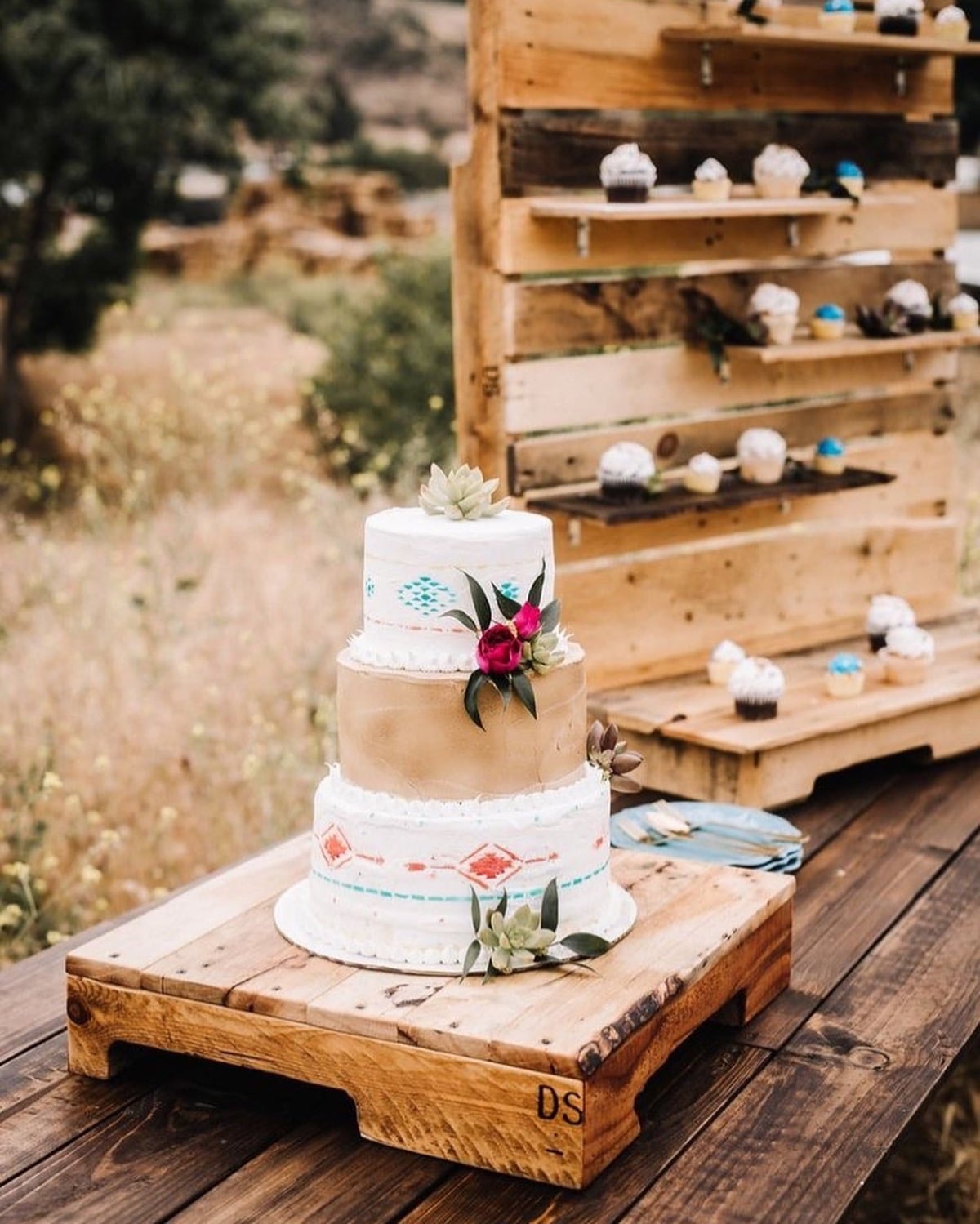 Small southwestern stitch-pattern wedding cake with a cupcake display made from pallet wood