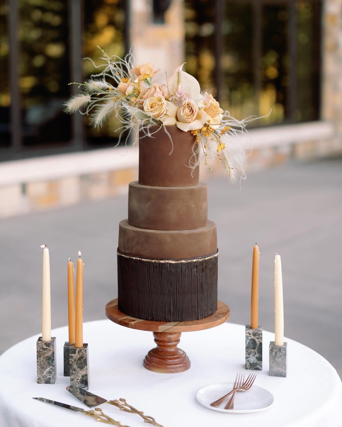 Mocha and chocolate ombre wedding cake with a chocolate bark bottom tier, peach roses, and pampas grass